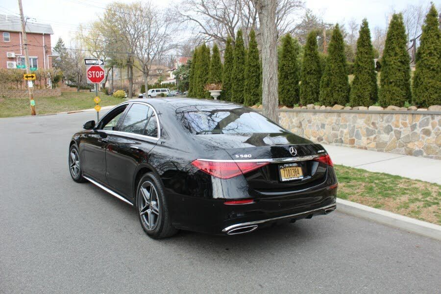 Black Mercedes sedan parked on a residential street with a stop sign.