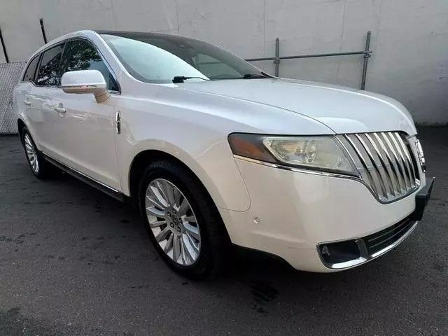 White Lincoln MKT SUV parked on asphalt, bright sunlight.