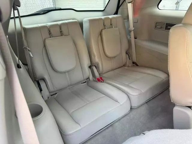 Beige leather car seats in the back of a vehicle, with a cup holder visible on the left.
