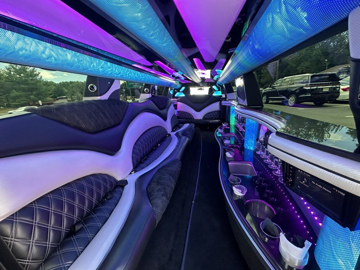 Inside of a luxury limousine with purple and blue lighting and black and white seats.