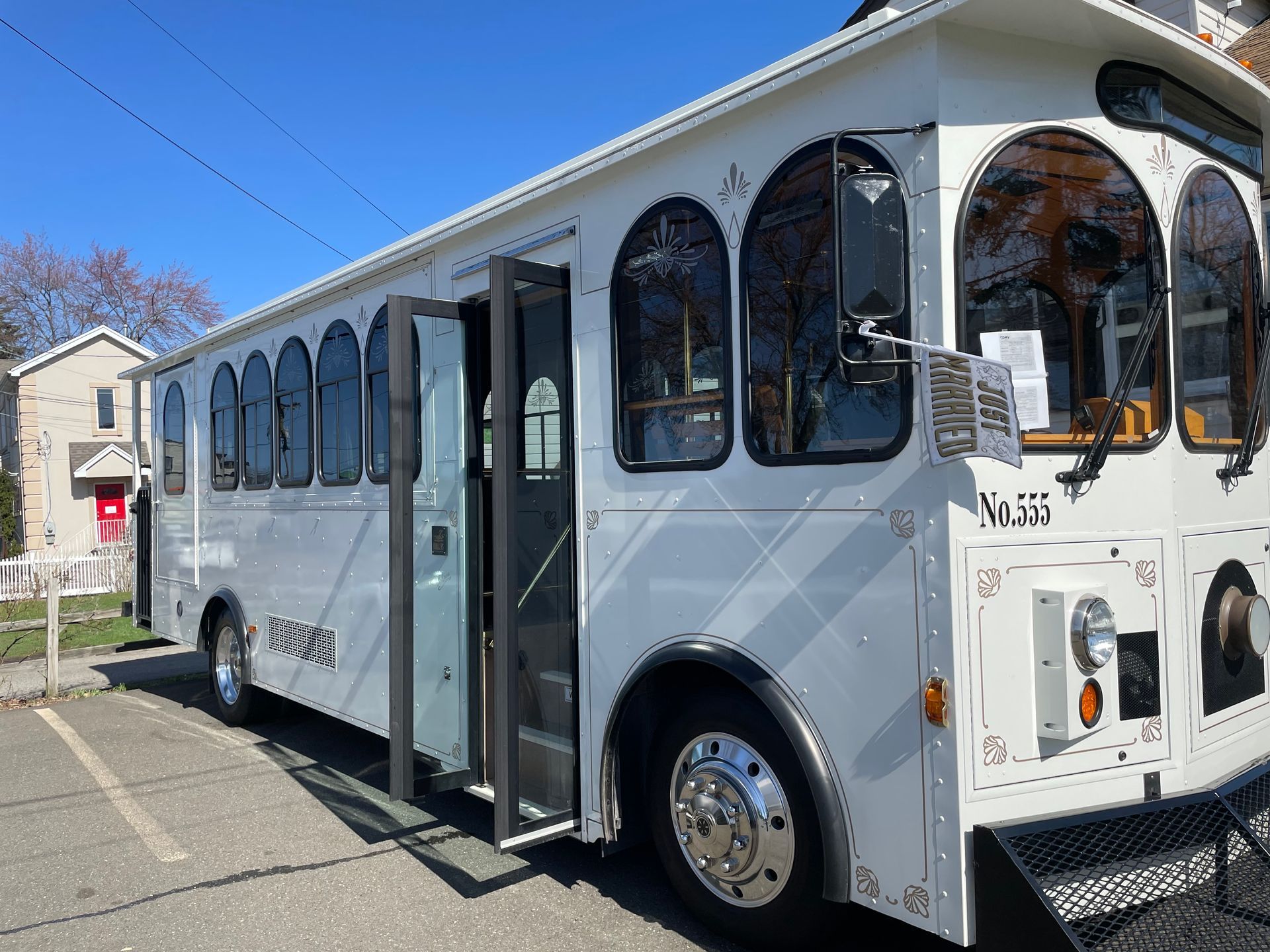 White trolley with open doors, parked outdoors on a sunny day.