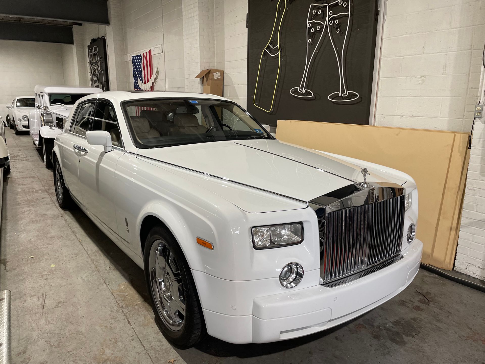White Rolls-Royce Phantom parked indoors with a silver grille and shiny chrome wheels.