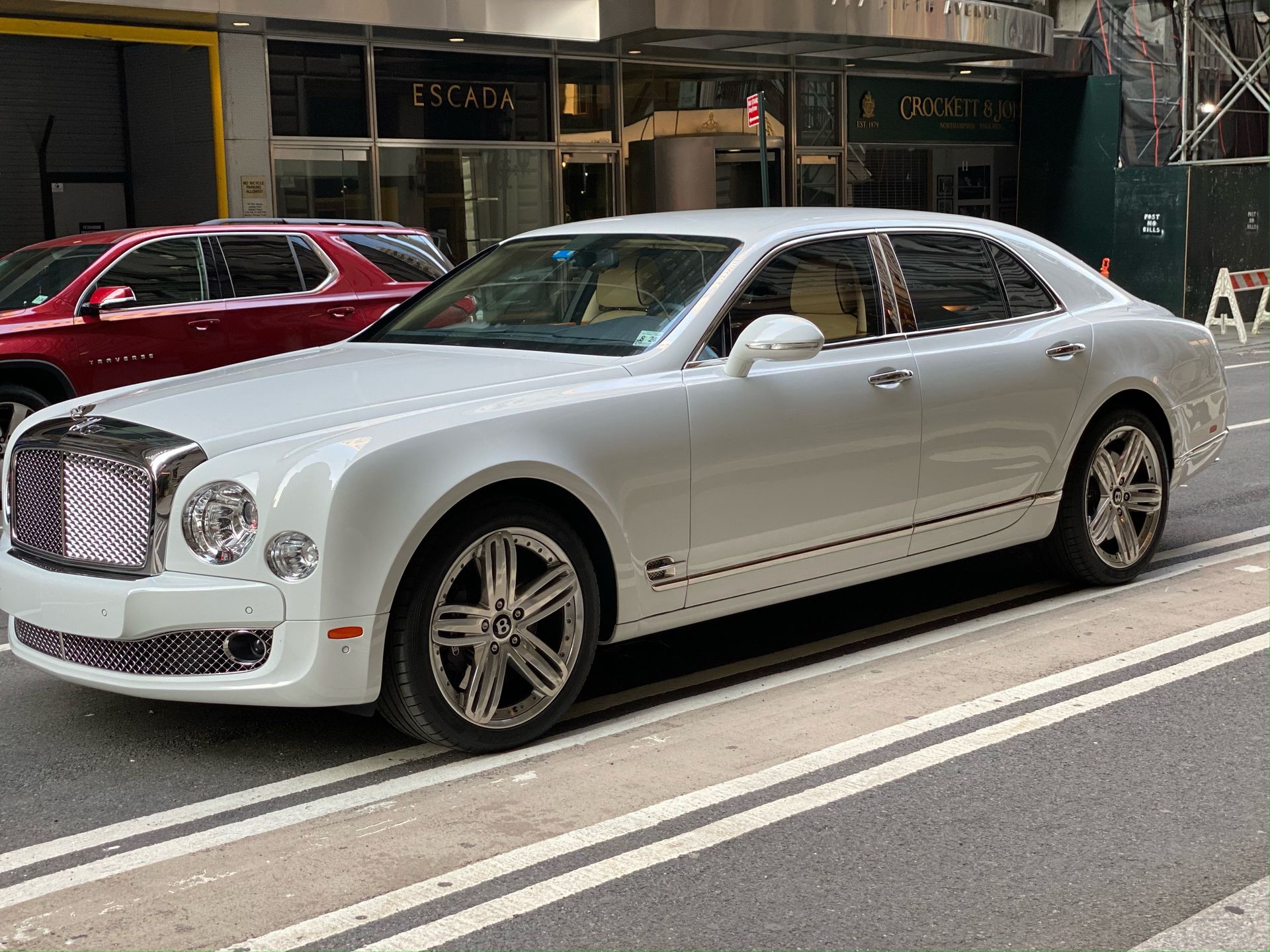 White Bentley Mulsanne parked on a city street, with a red SUV visible behind it.