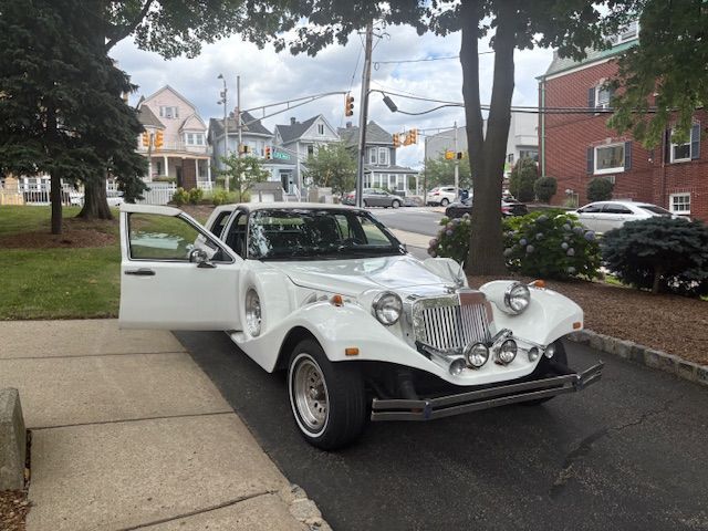 White classic car parked on a city street with its door open.