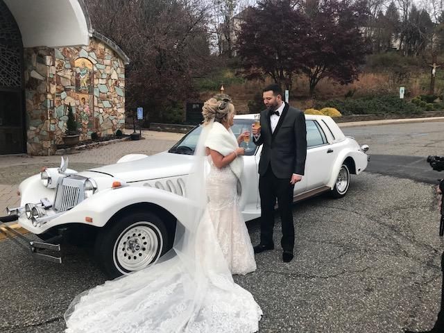 Bride and groom near a white classic car. The couple is toasting with champagne.