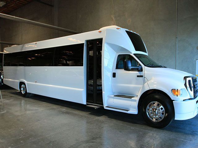 White party bus parked indoors with open door.