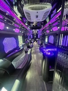 Interior of a party bus with purple and black accents, mirrored ceiling, and seating.