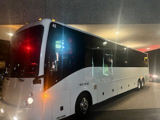 White charter bus parked in a dimly lit area, with the number 42 on the front.