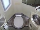 Small, clean airplane restroom with a toilet, two sinks, and a window.