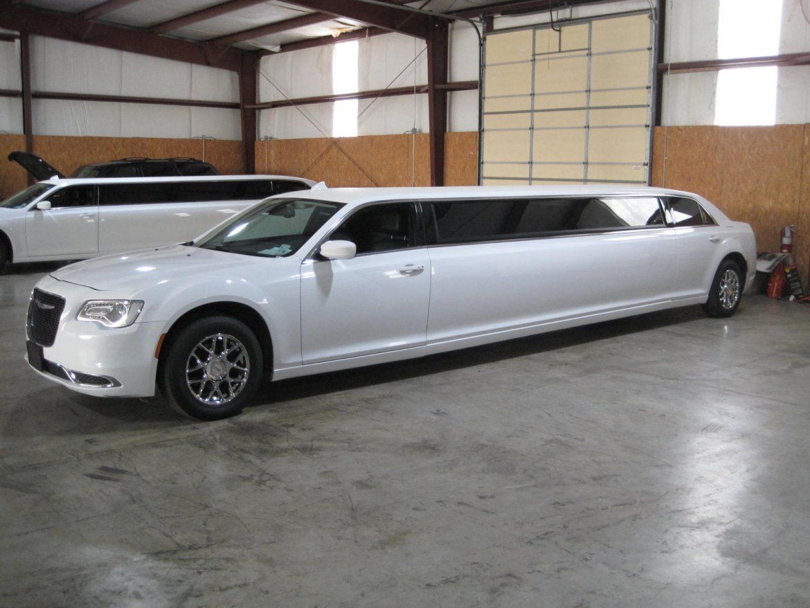 White limousine inside a garage, another limousine in the background.