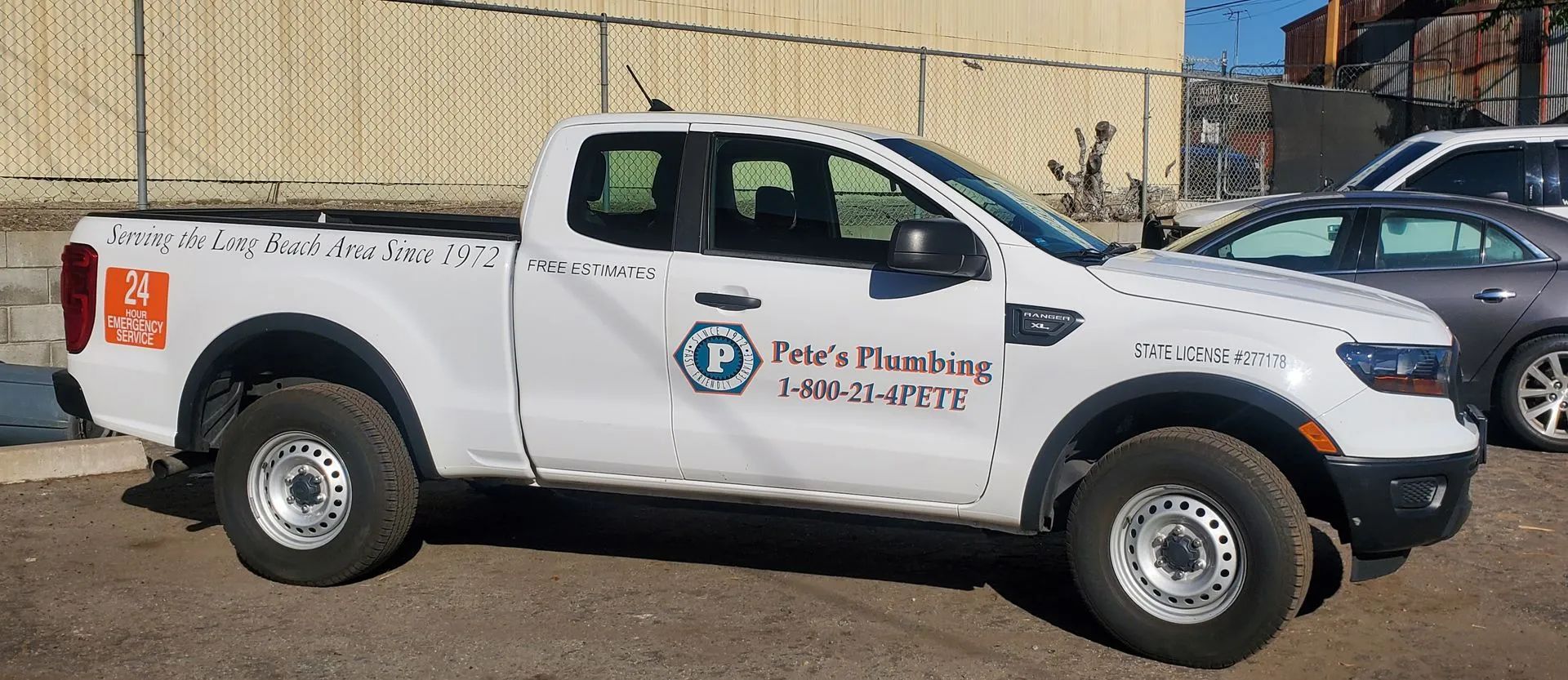 White Ford pickup truck with plumbing company logo on side.