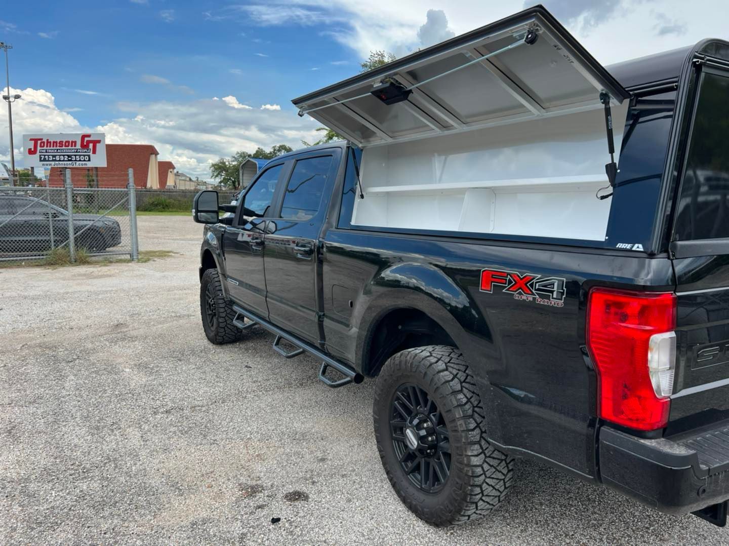 Black pickup truck with an open cap, parked outside.