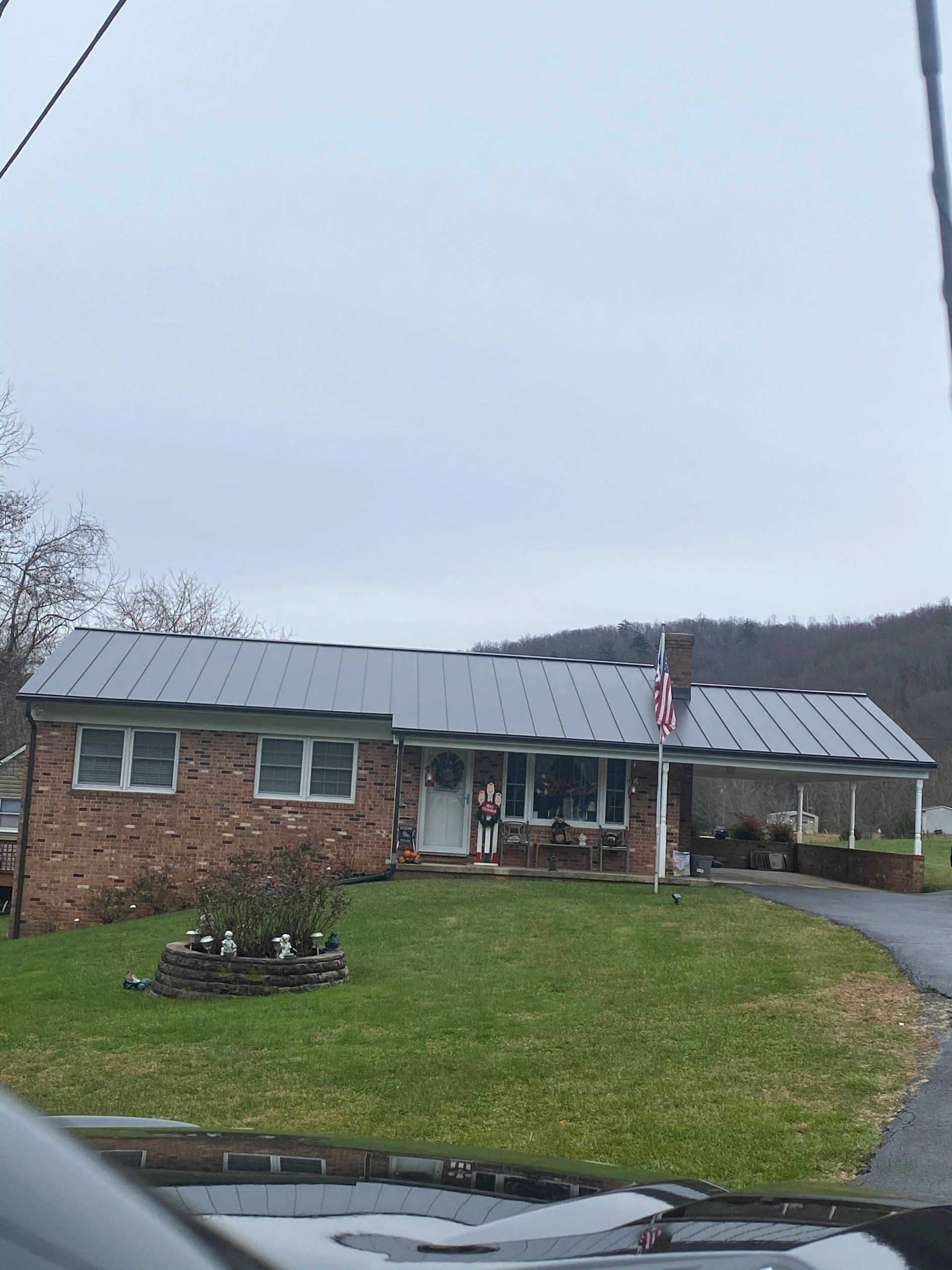 A brick house with a metal roof is sitting in the middle of a grassy field.