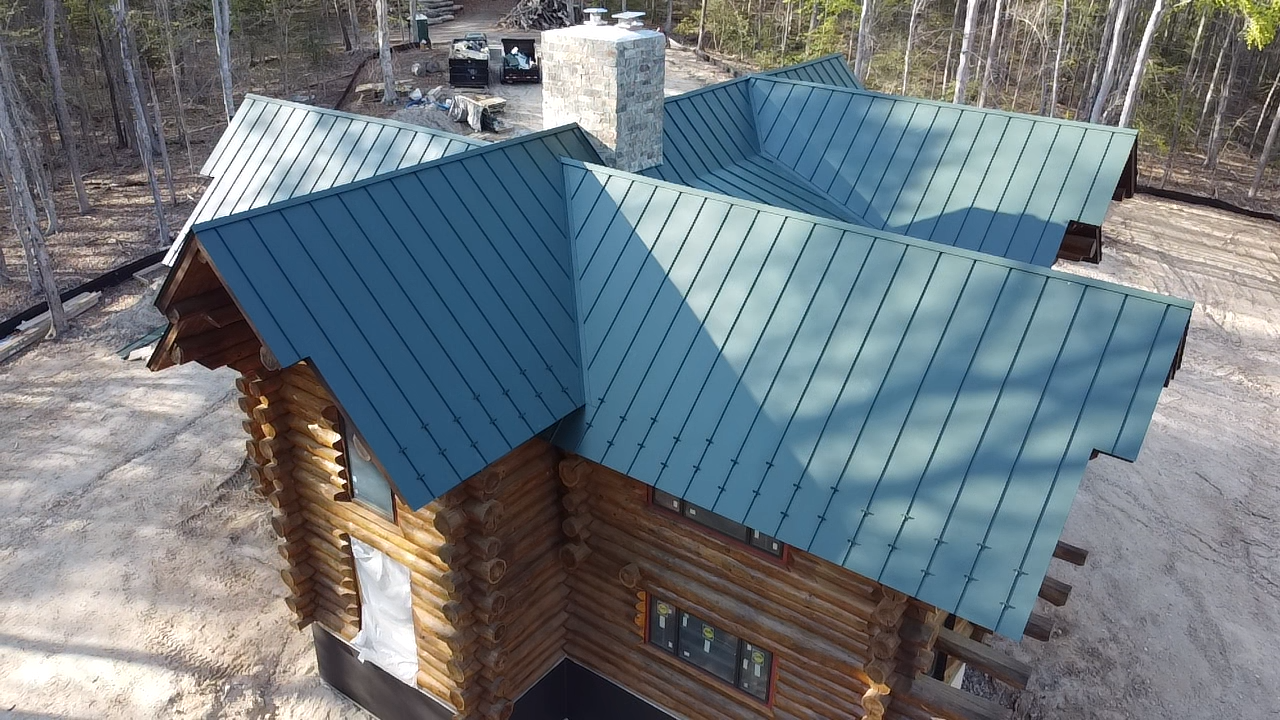 An aerial view of a log cabin with a green roof.