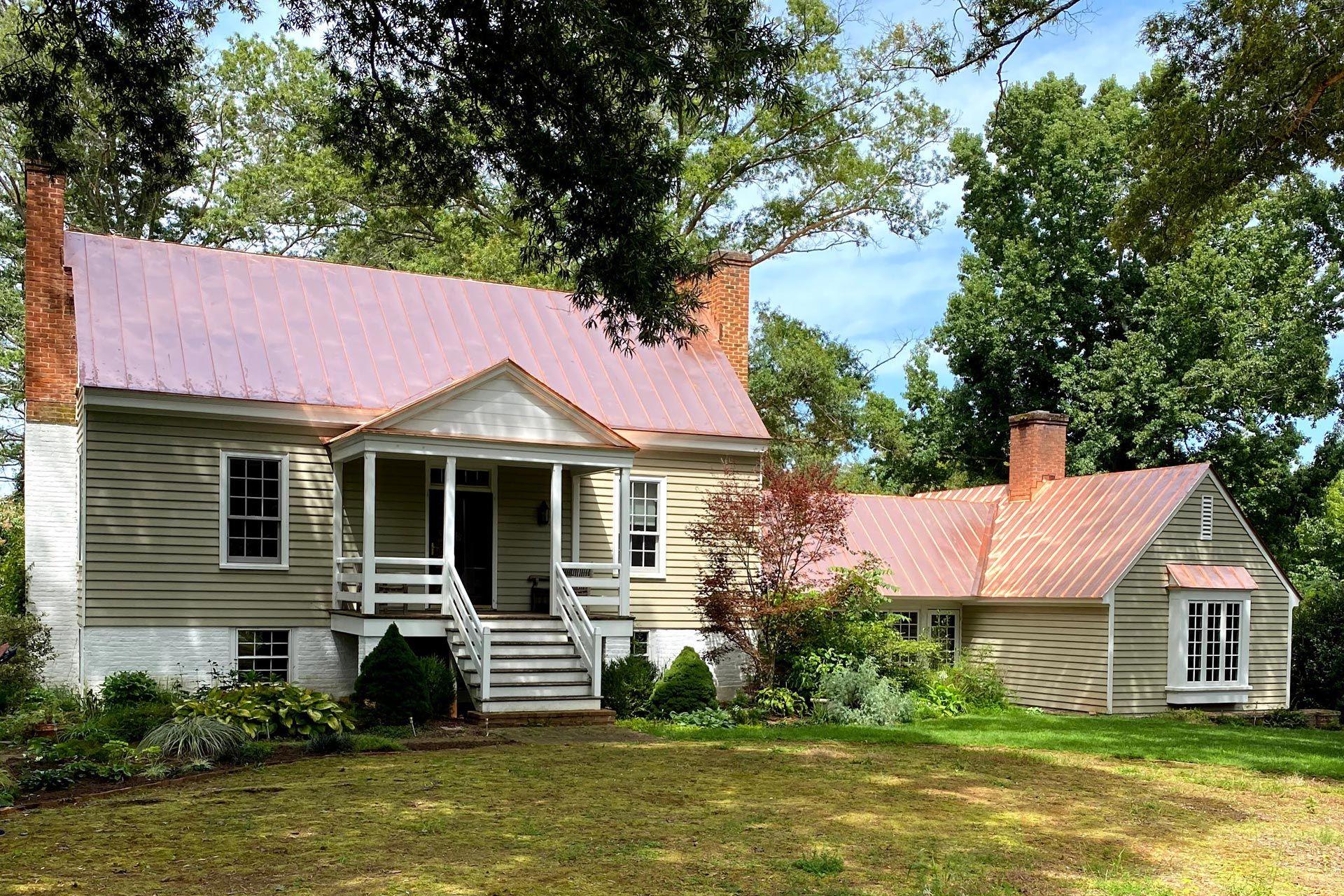 A large house with a pink roof is surrounded by trees