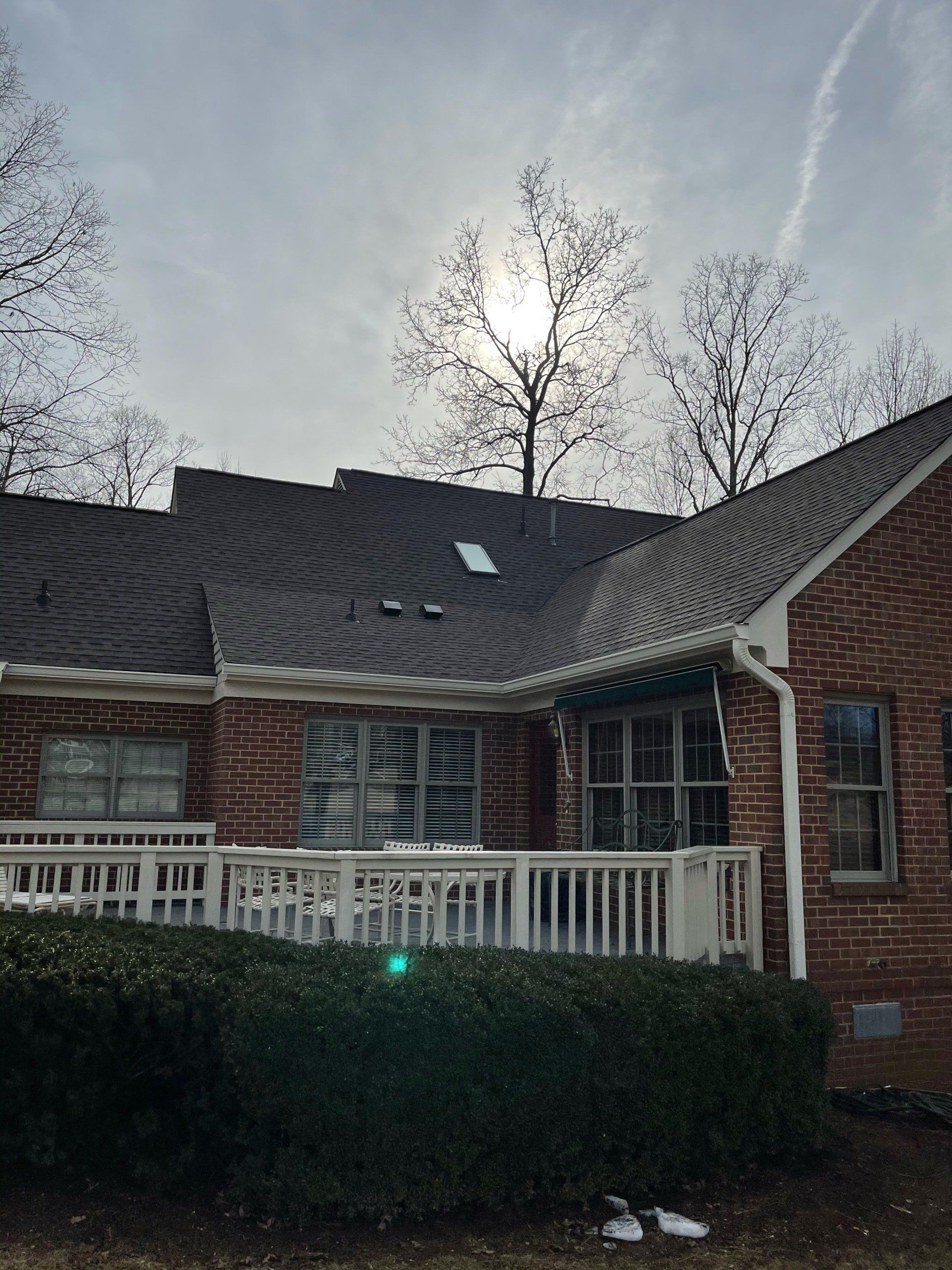 A brick house with a balcony and a roof with a skylight.