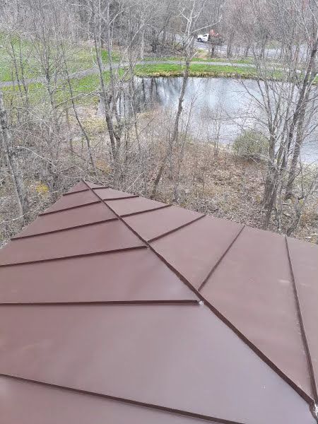 A brown roof with a view of a lake and trees.