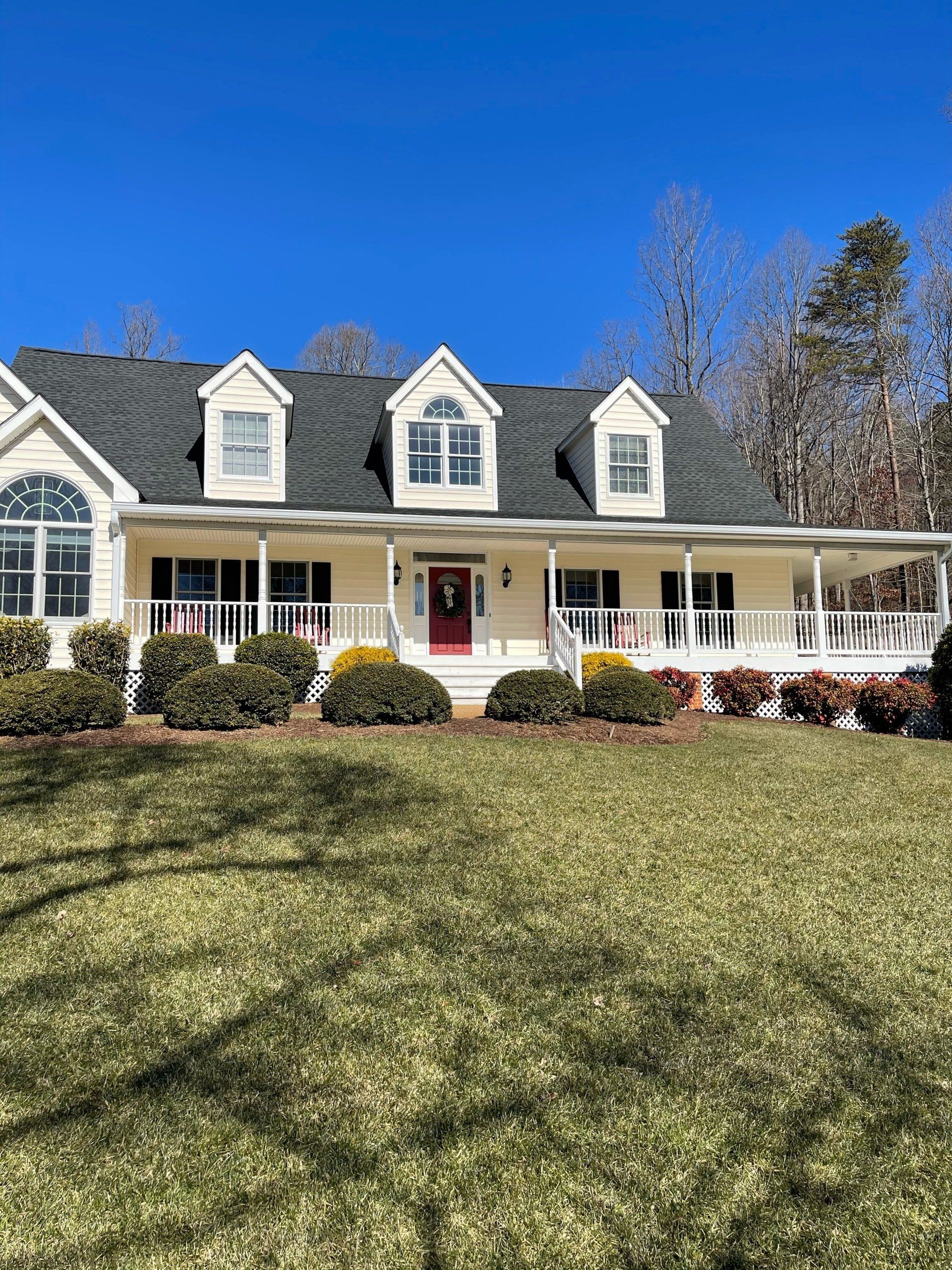 A large white house with a large porch and a red door.