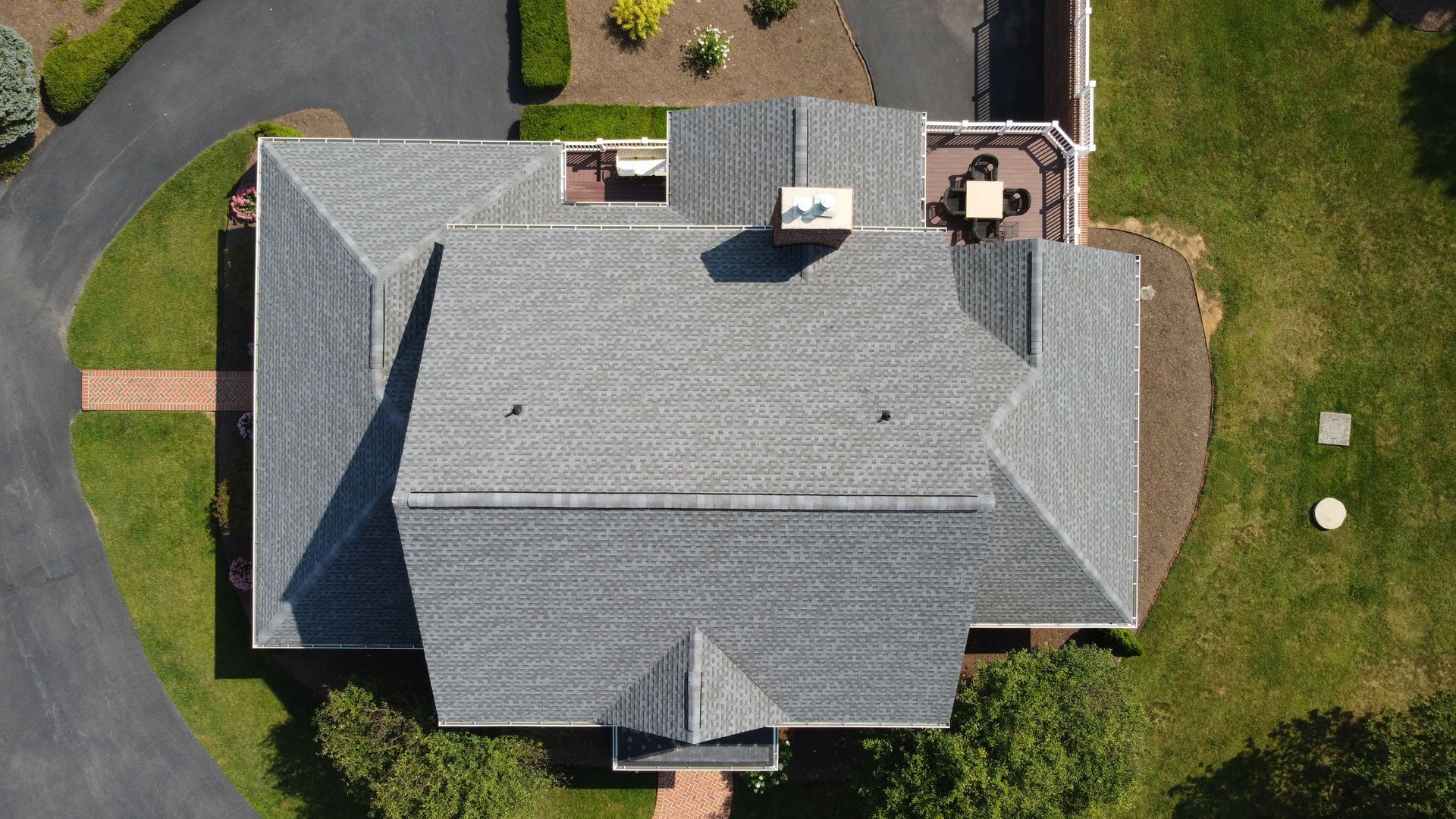 An aerial view of a large house with a gray roof and a driveway.