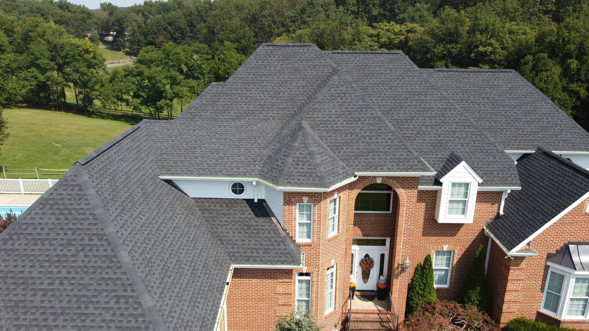 An aerial view of a large brick house with a gray roof