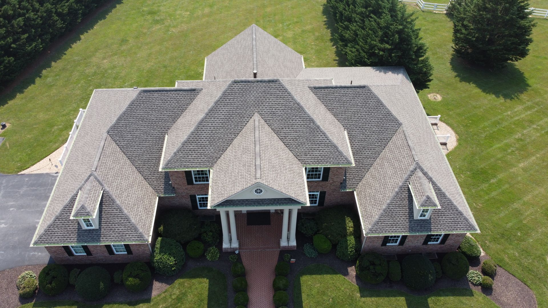 An aerial view of a large brick house with a gray roof