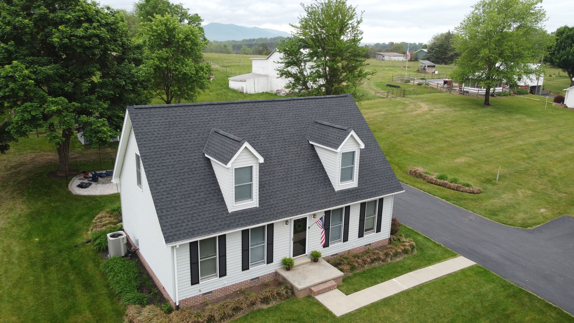 An aerial view of a white house with a black roof.