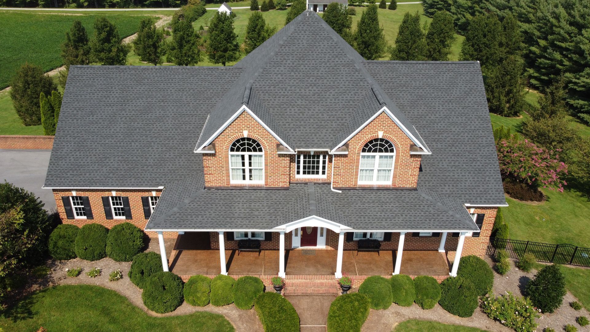 An aerial view of a large brick house with a black roof
