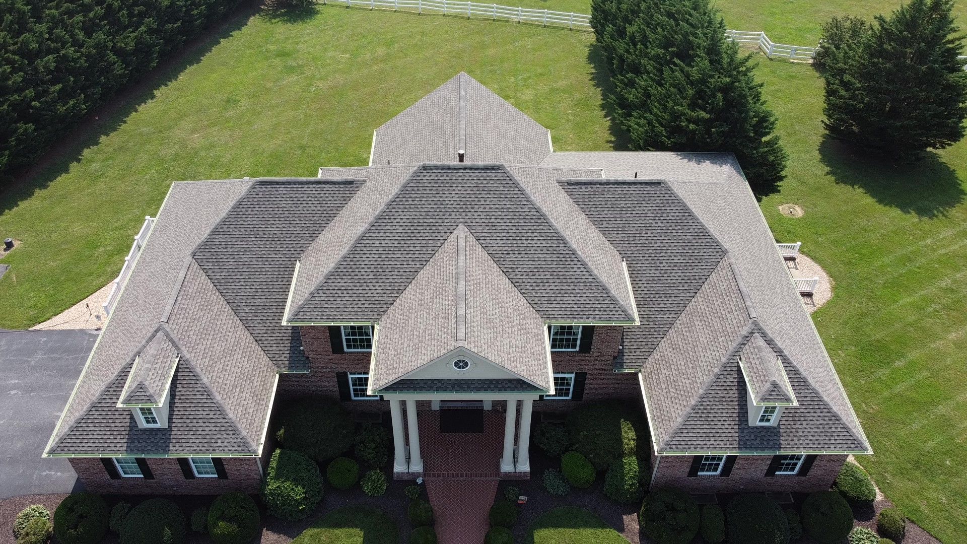 An aerial view of a large brick house with a large roof
