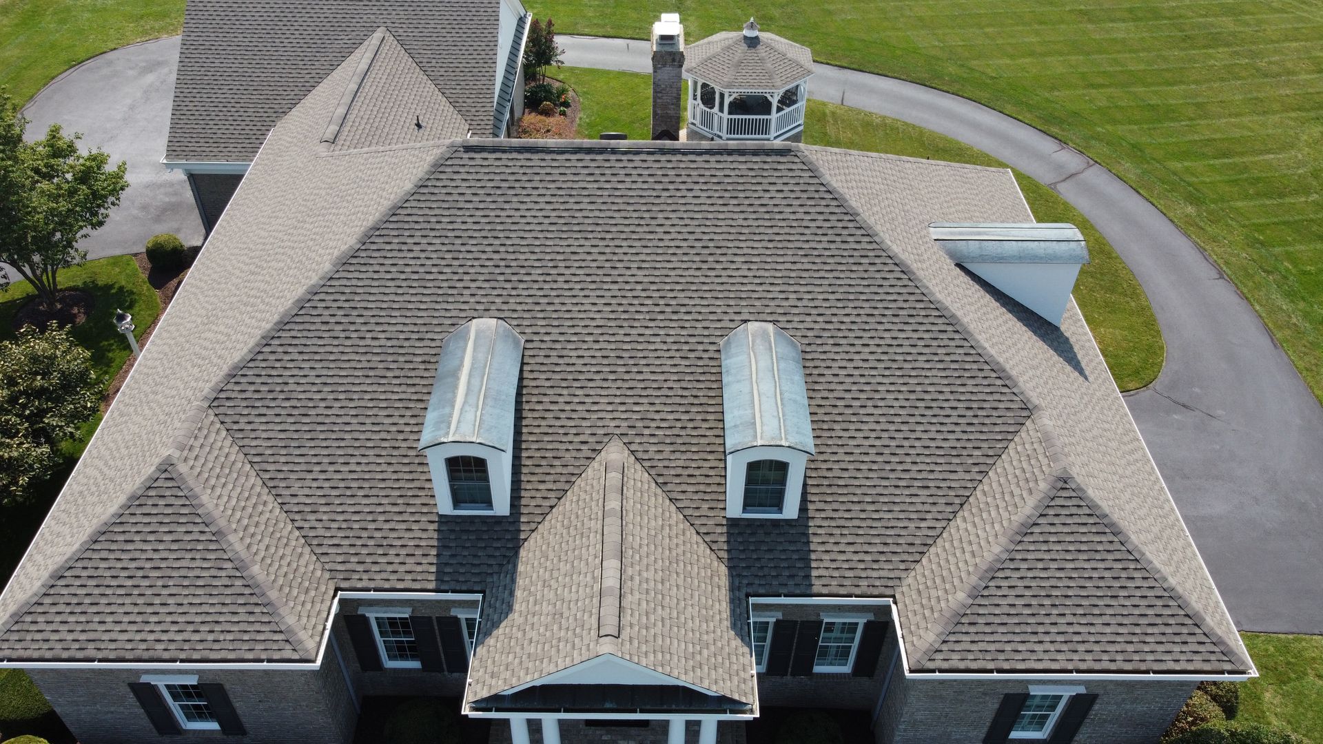 An aerial view of a large house with a gazebo in the background.