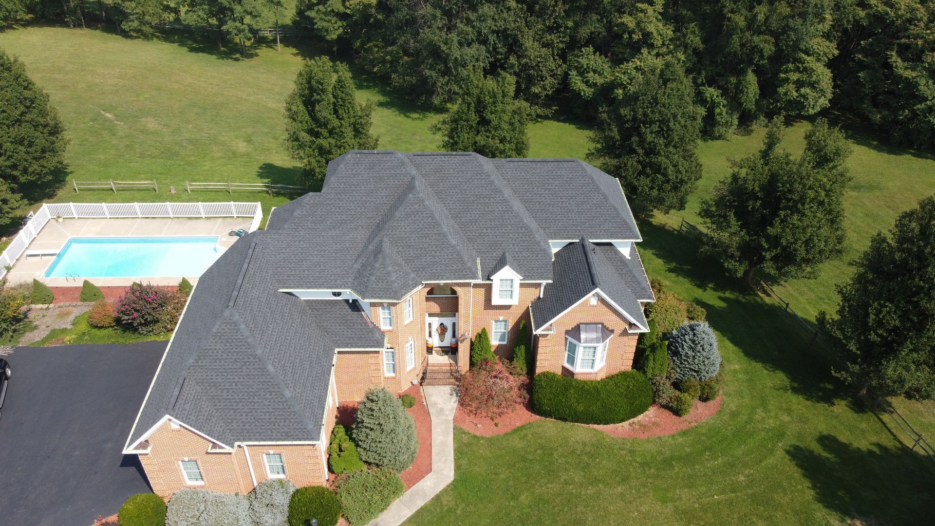 An aerial view of a large brick house with a pool in the backyard.