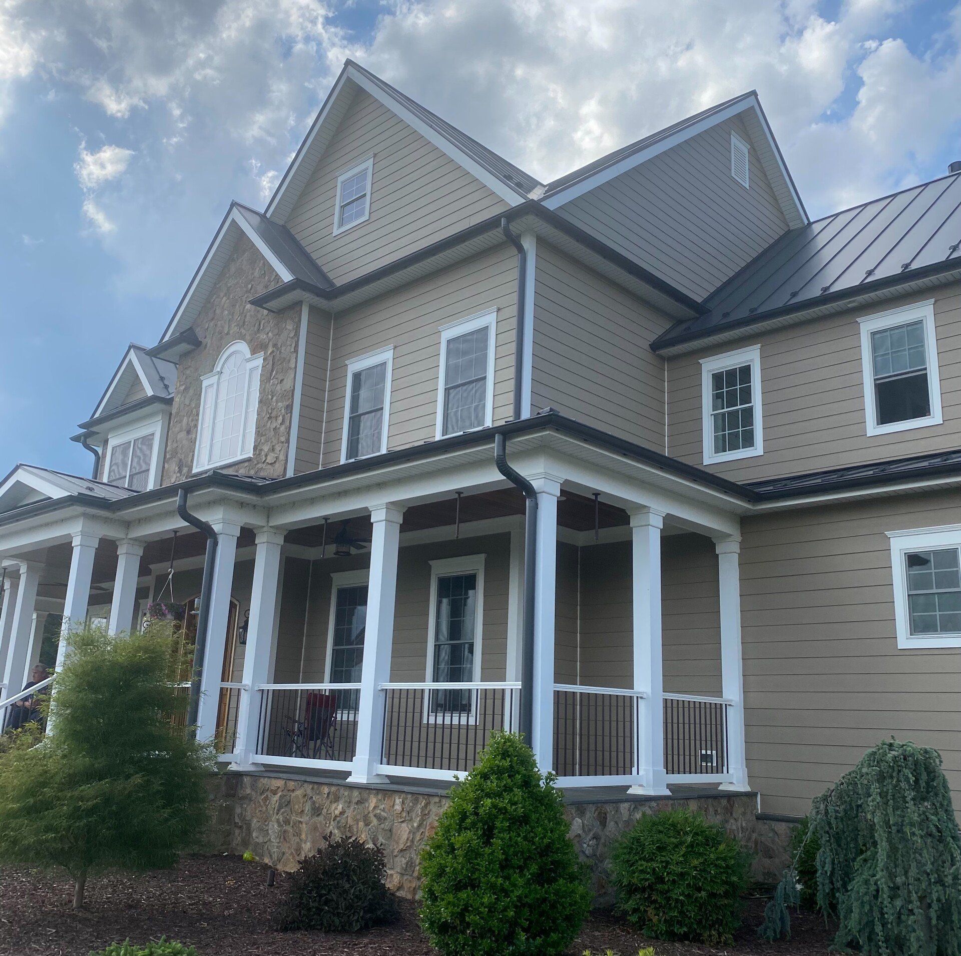 A large house with a porch and a metal roof