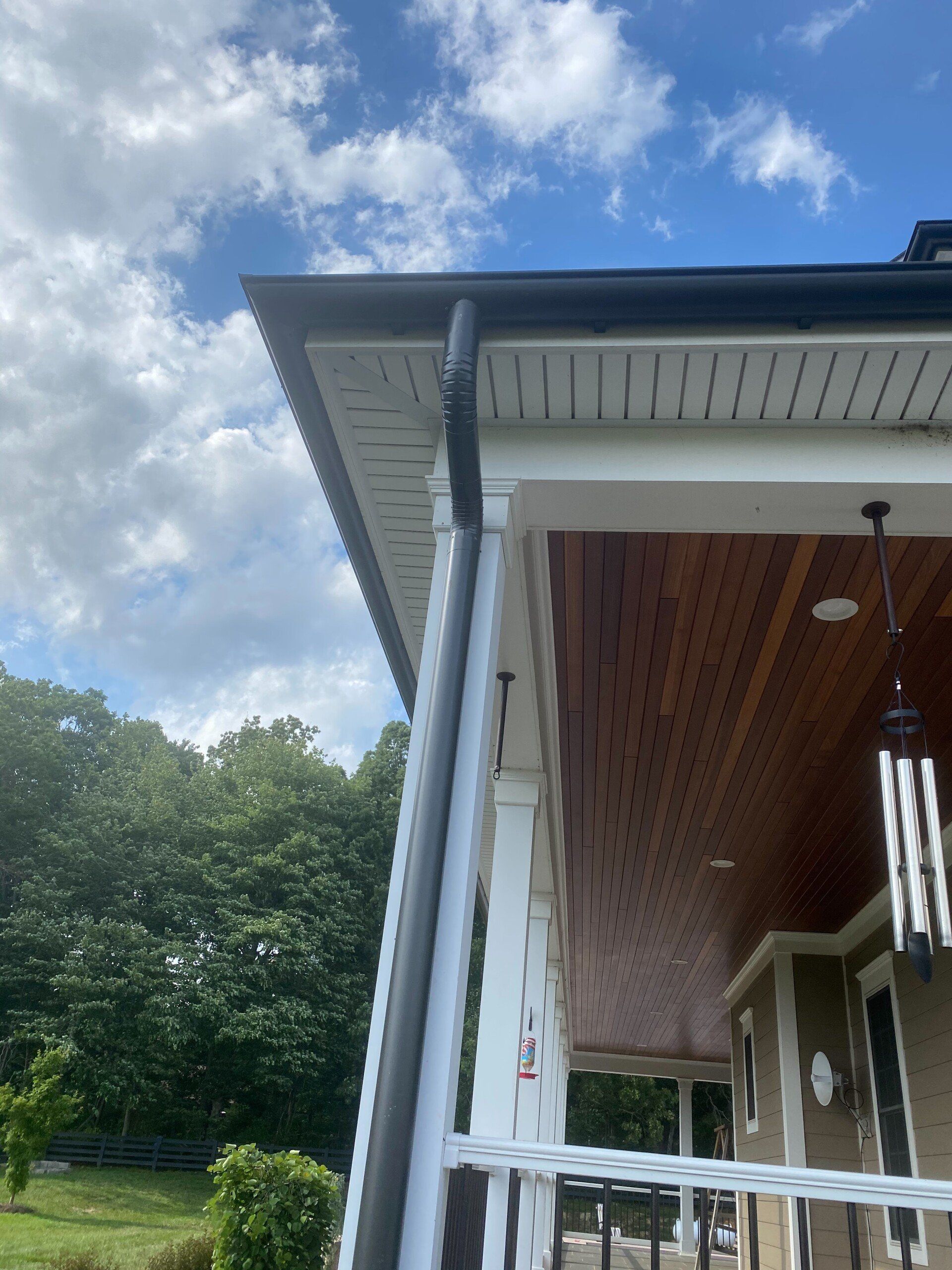 A house with a porch and a gutter on the side of it.