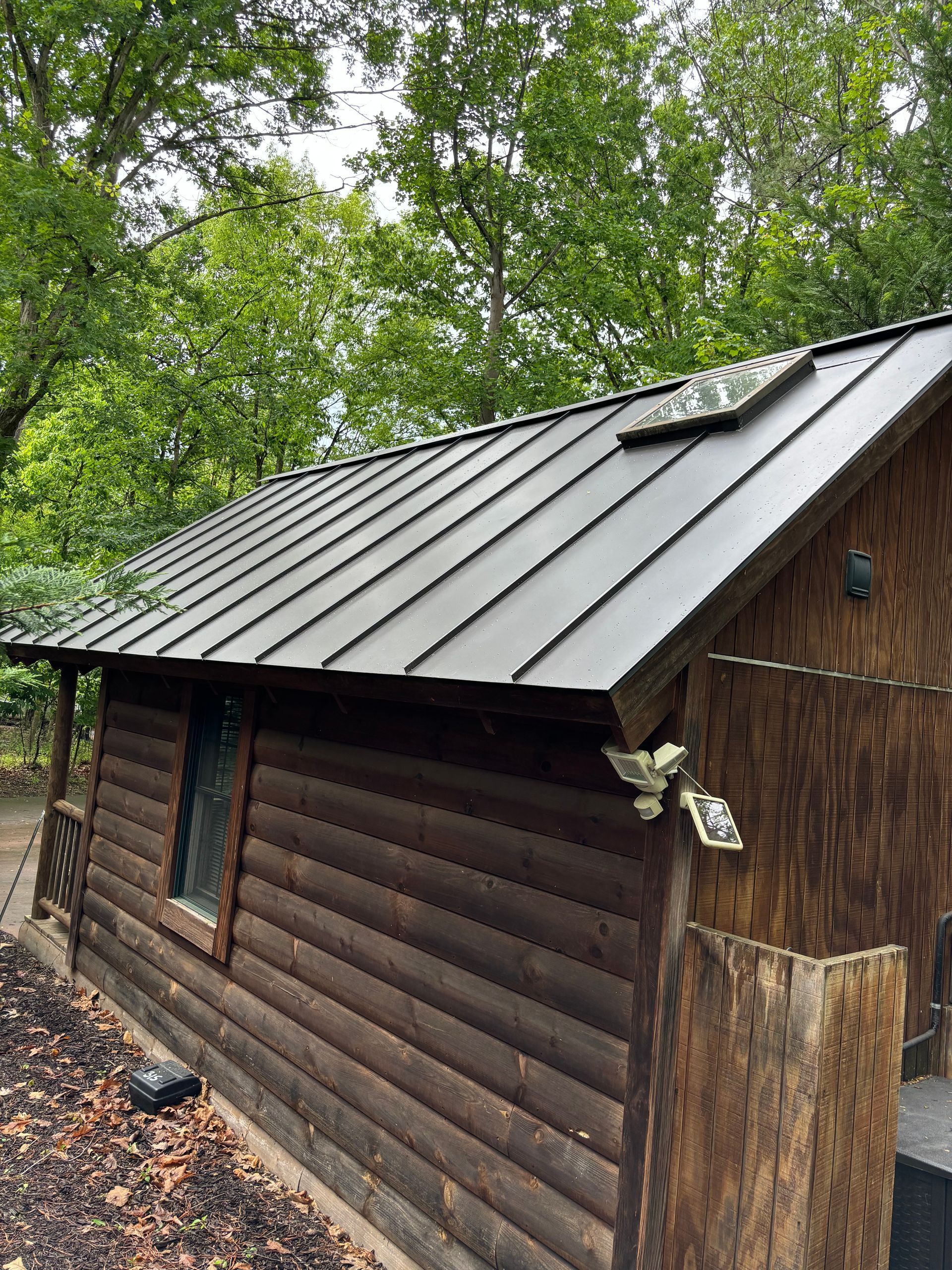 A log cabin with a metal roof in the woods.