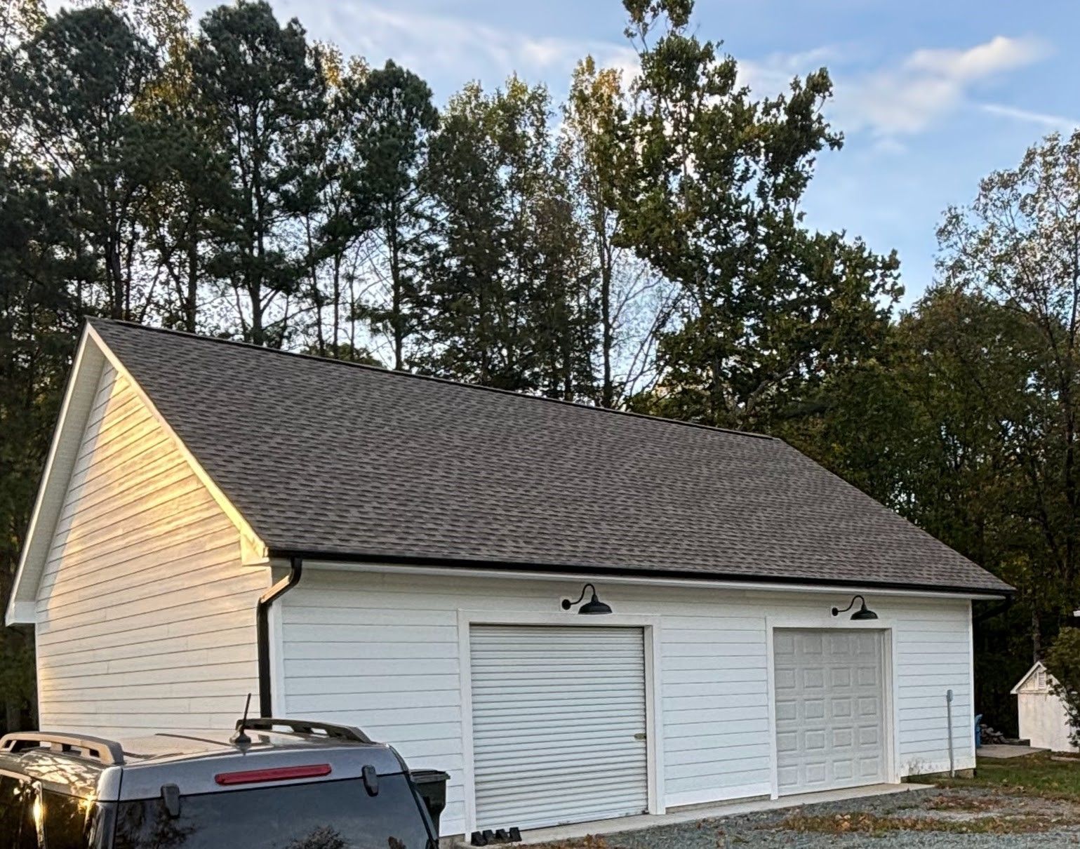 A white garage with a car parked in front of it.