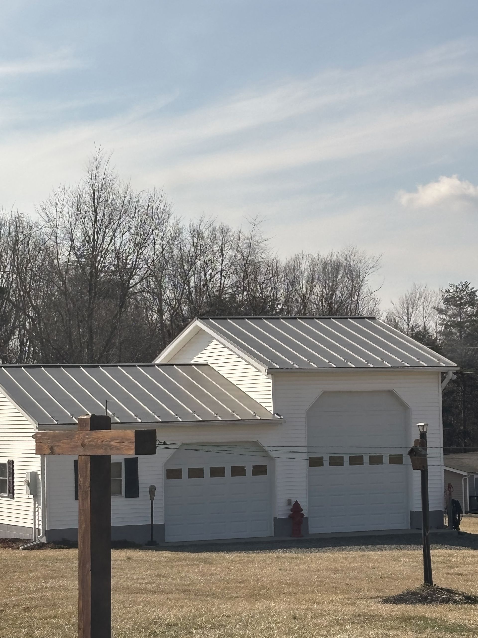 A white house with a metal roof and a wooden cross in front of it