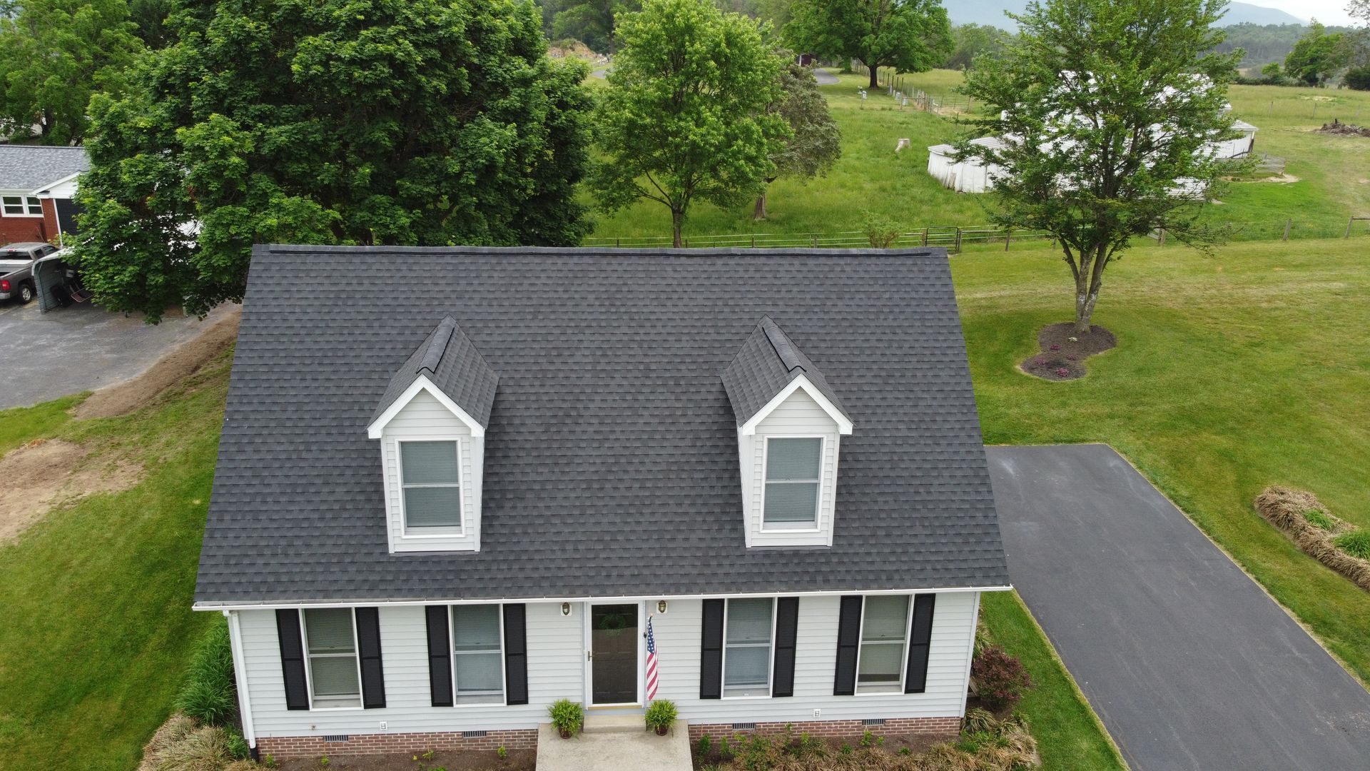 An aerial view of a white house with a black roof and black shutters.