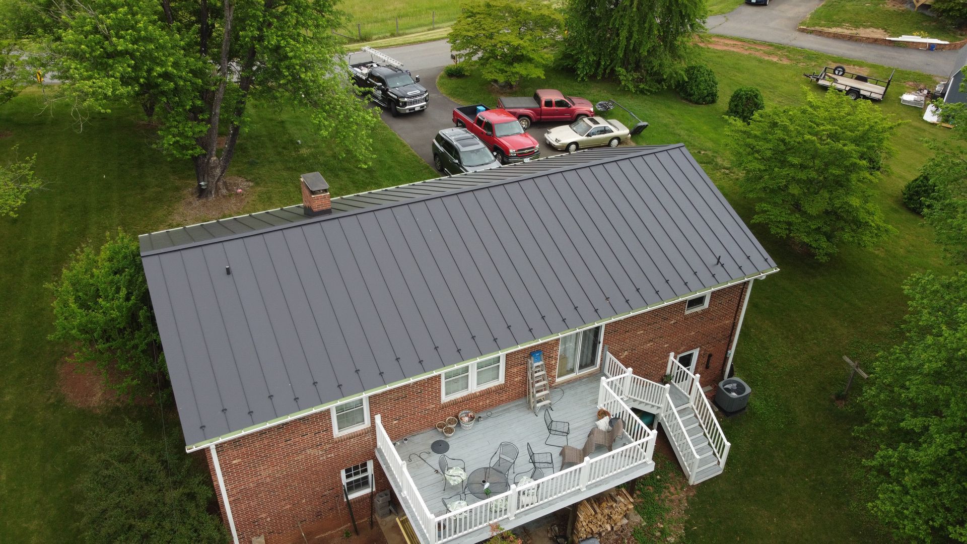 An aerial view of a house with a black roof and a large deck.
