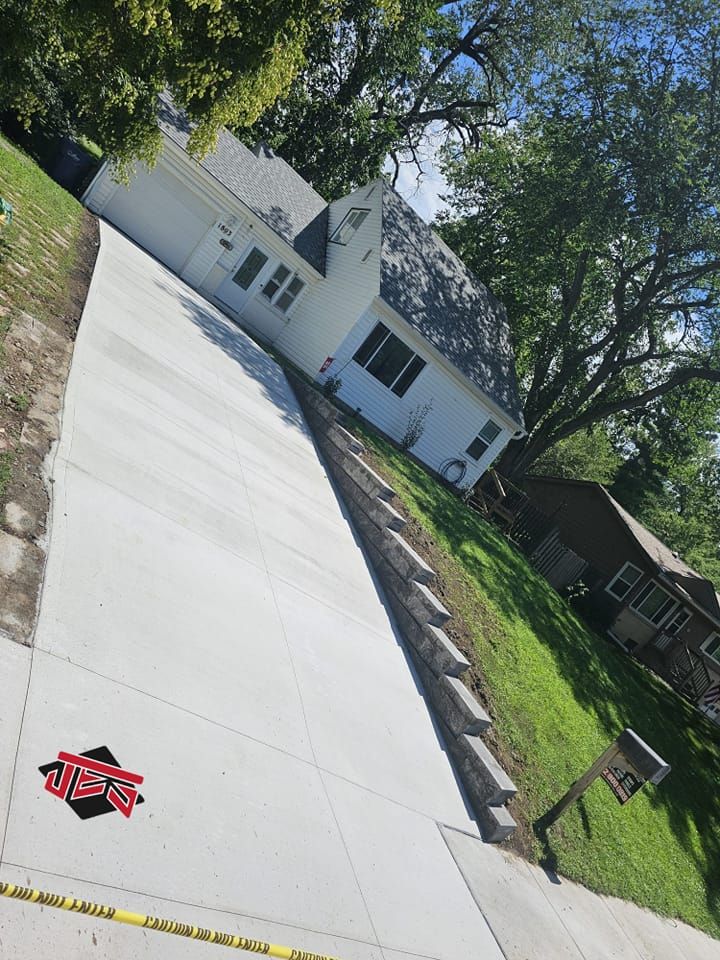 A white house is sitting next to a concrete driveway