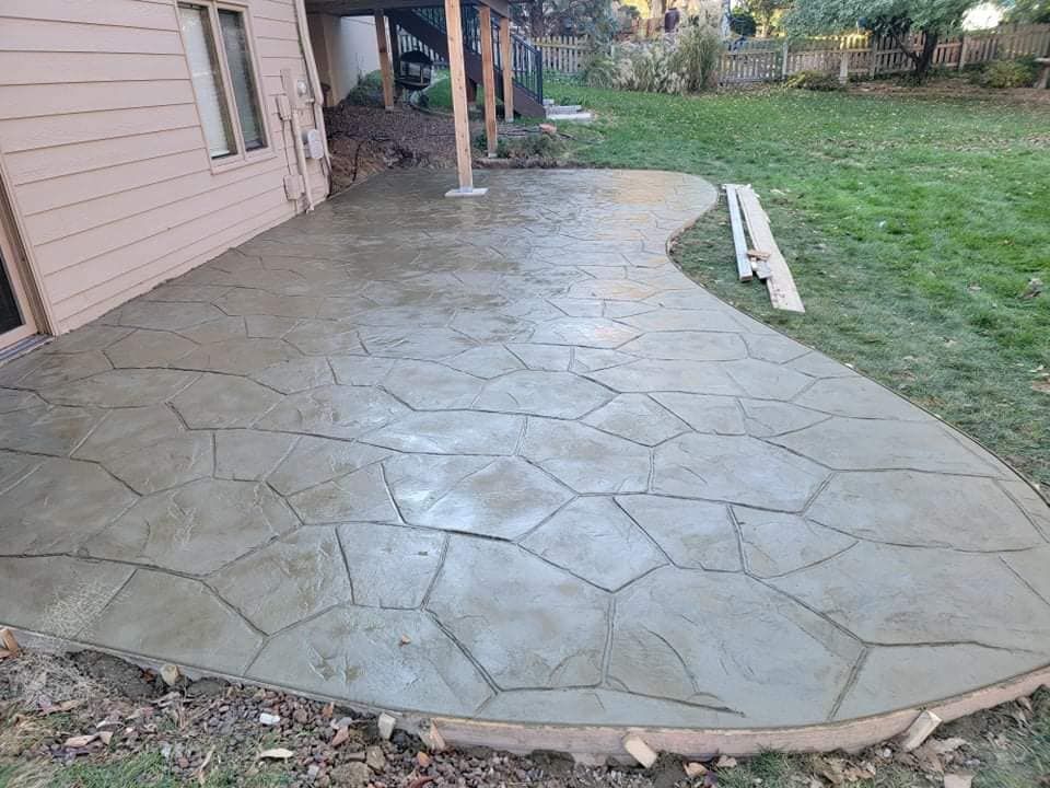A concrete patio is being built in the backyard of a house
