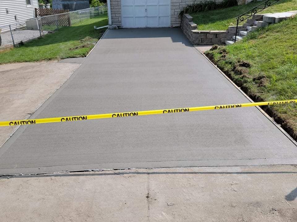 A concrete driveway with a yellow caution tape around it