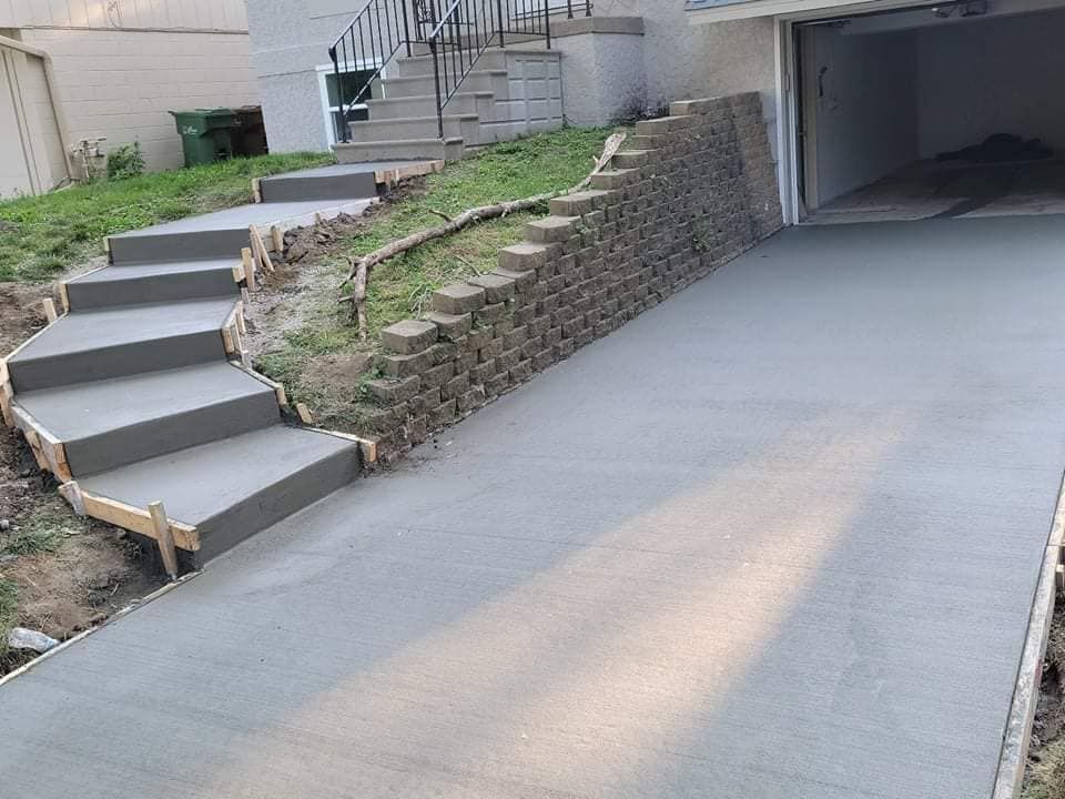 A concrete driveway with stairs leading up to a garage