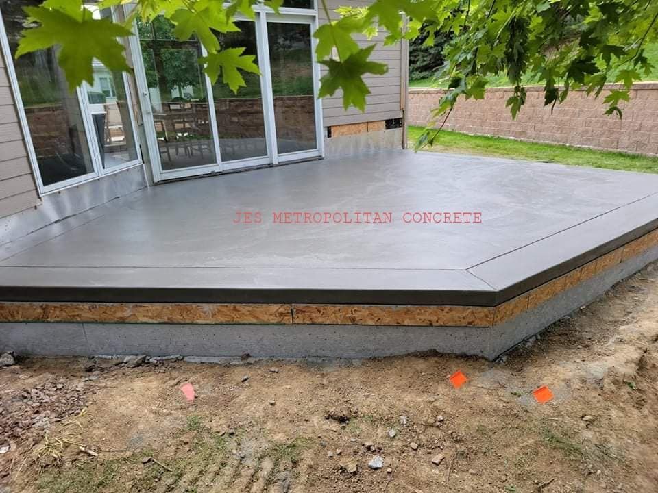 A concrete deck is being built in front of a house