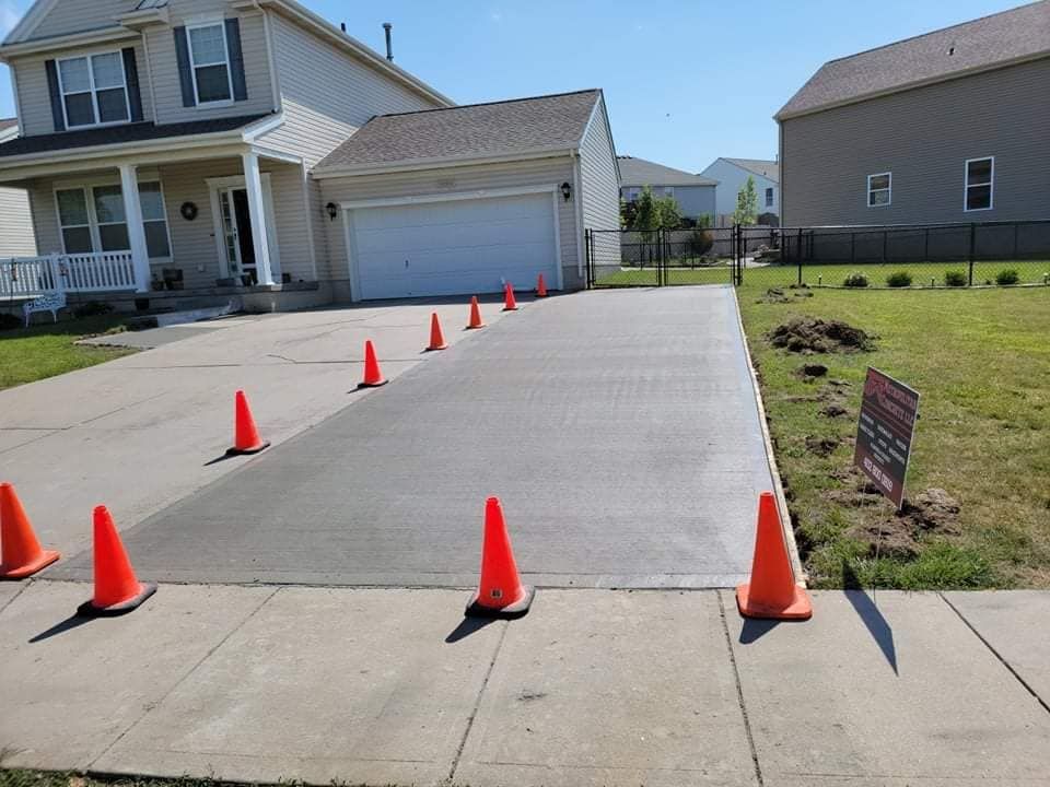 A row of orange traffic cones on a concrete driveway in front of a house