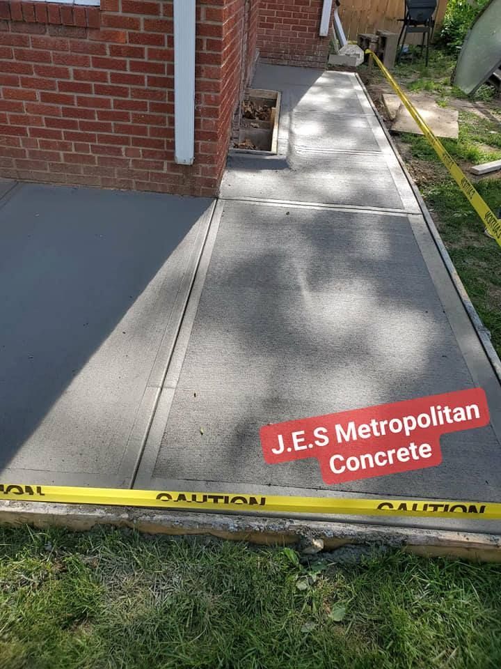 A concrete walkway is being built in front of a brick house