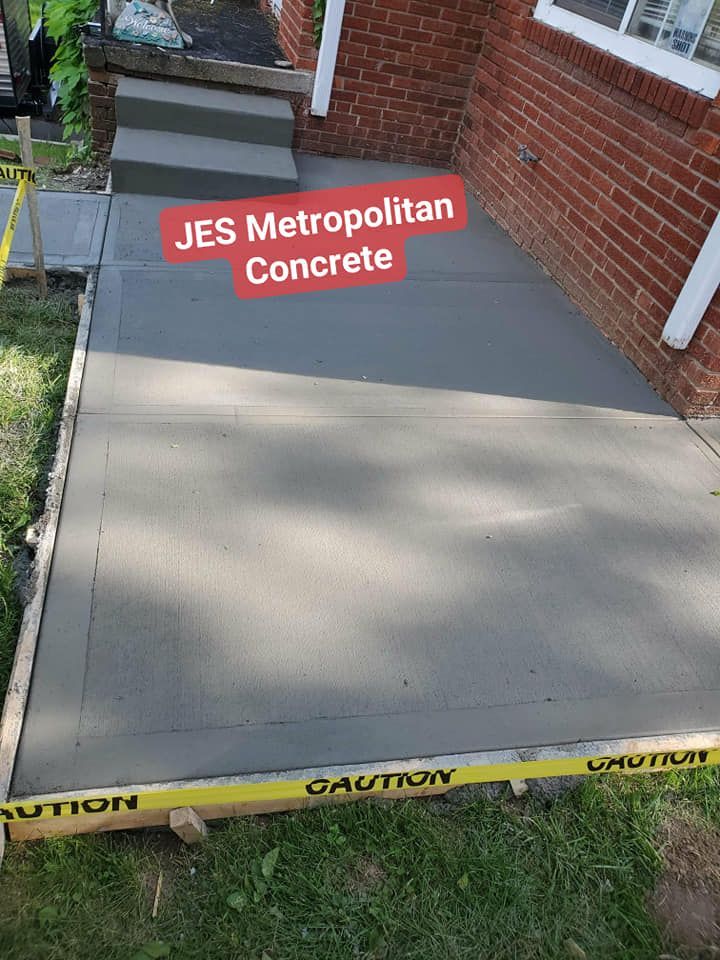 A concrete walkway is being built in front of a brick house