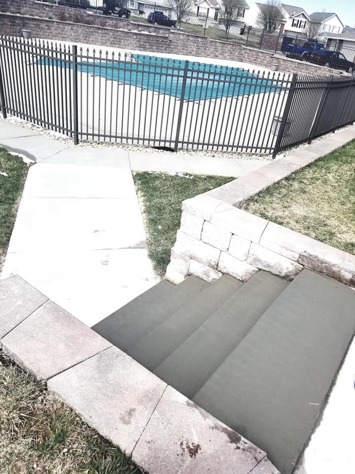 A swimming pool behind a fence with stairs leading to it