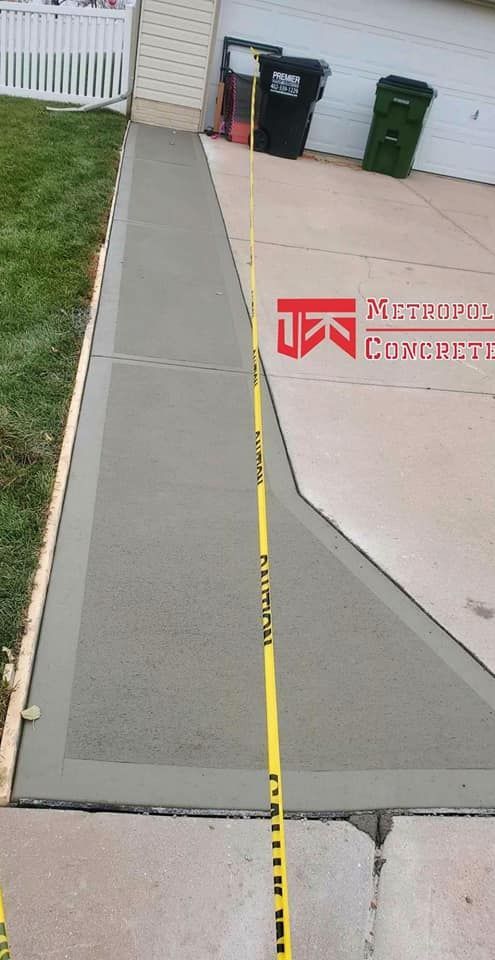 A concrete walkway is being built in front of a house