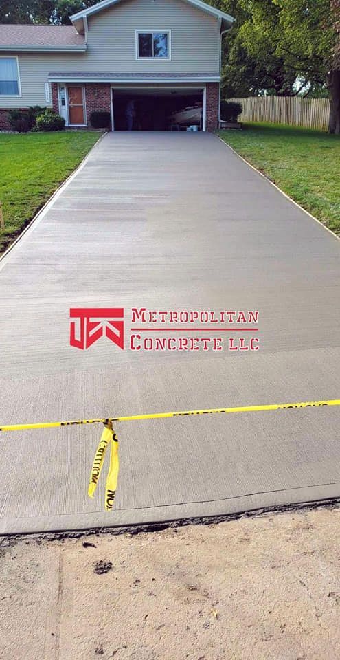 A concrete driveway leading to a house with a yellow tape