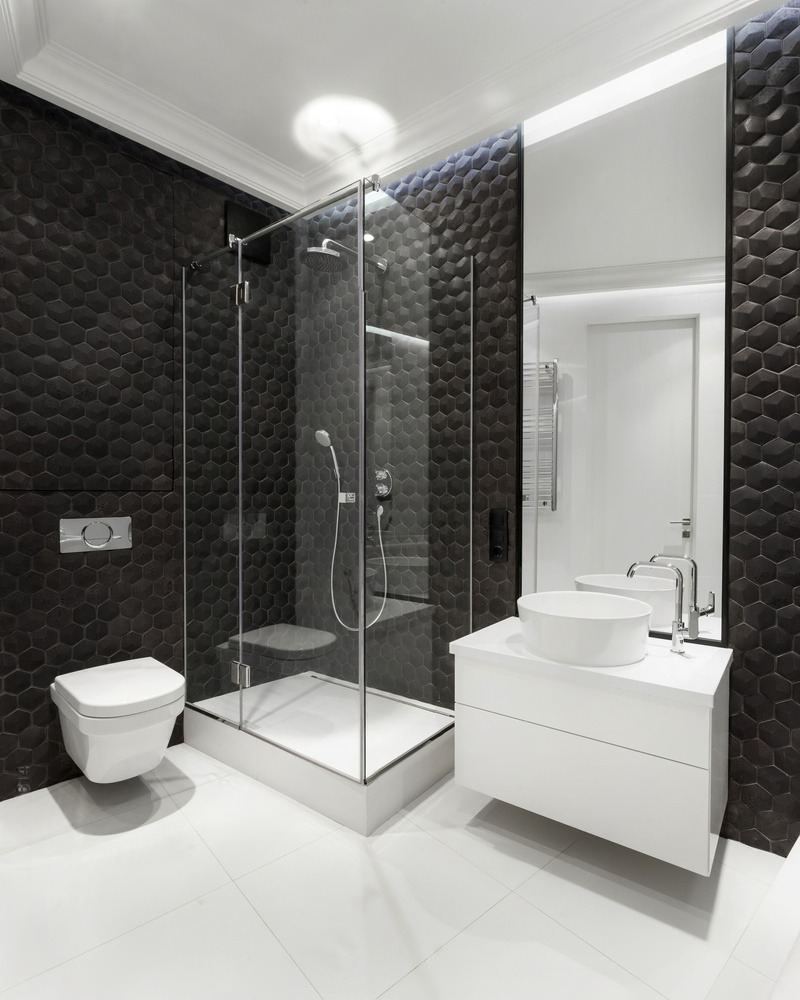 Modern black and white bathroom with a glass shower, floating toilet, and a vanity.