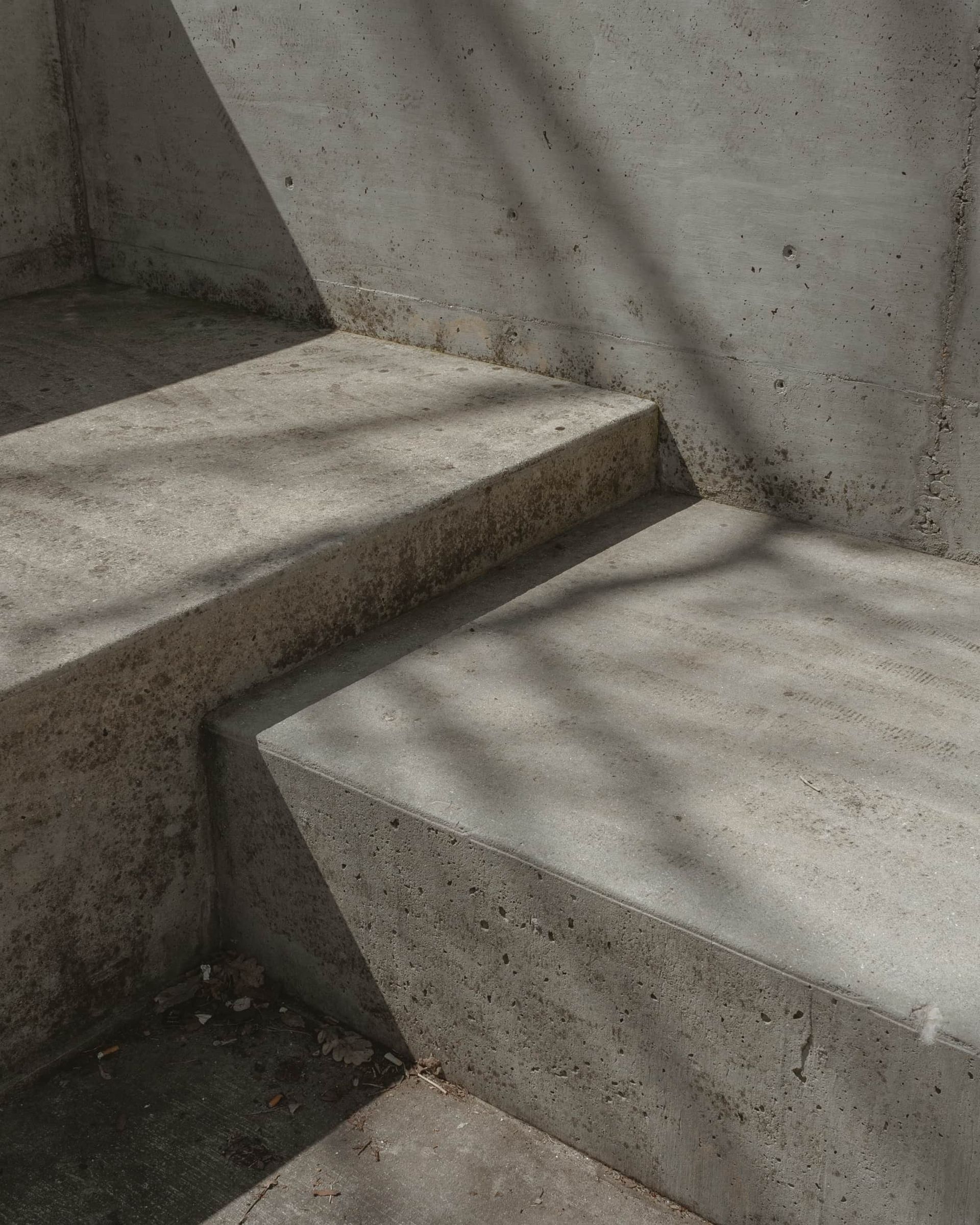 A close-up of a set of concrete stairs with a tree shadow on them.